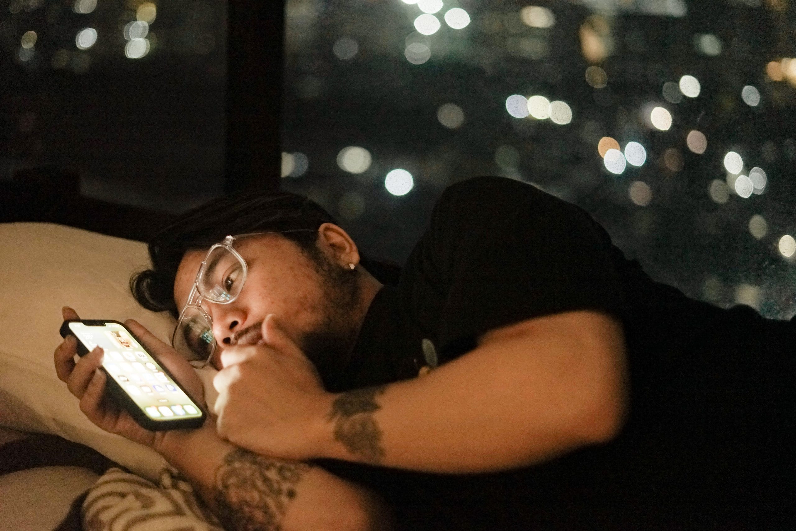 Man staring at phone while sitting in bed.