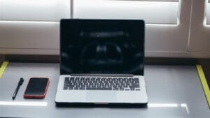 Smartphone beside a laptop and pen on a minimalist desk