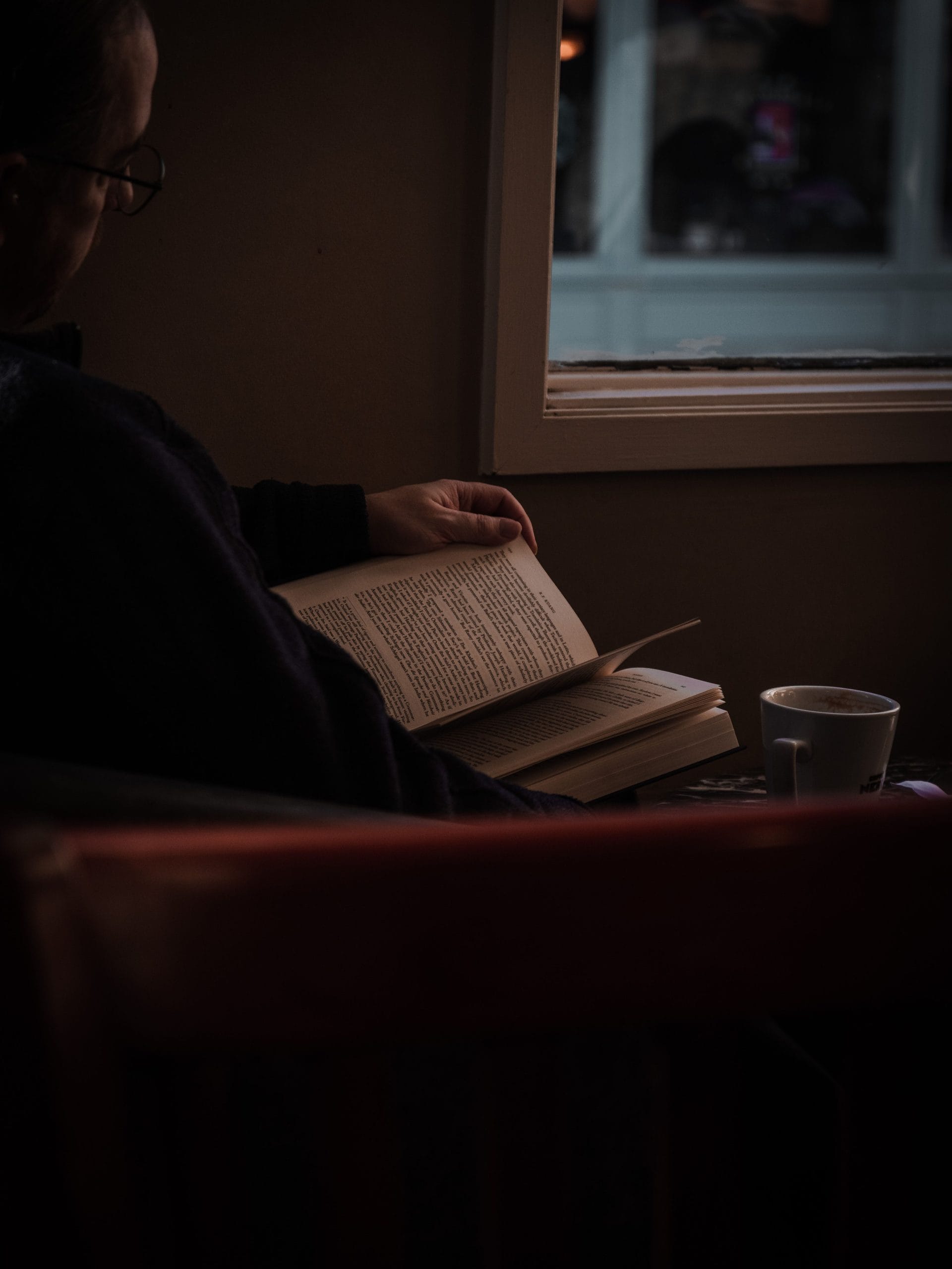 Man reading a book by the window.