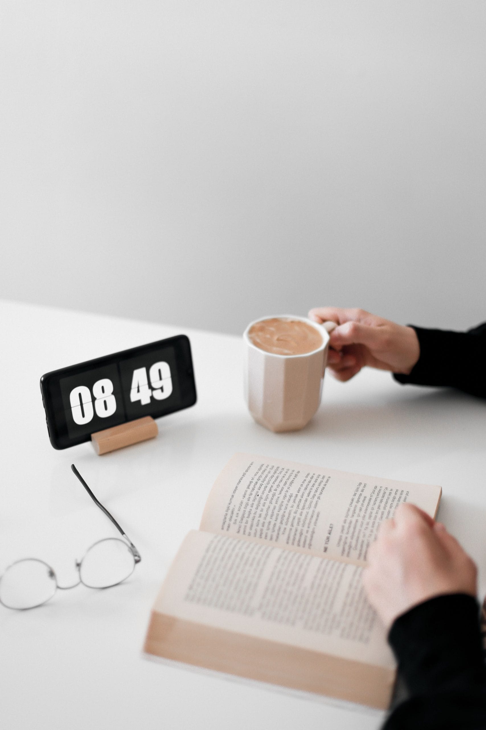 Man using phone as clock, while reading a book.