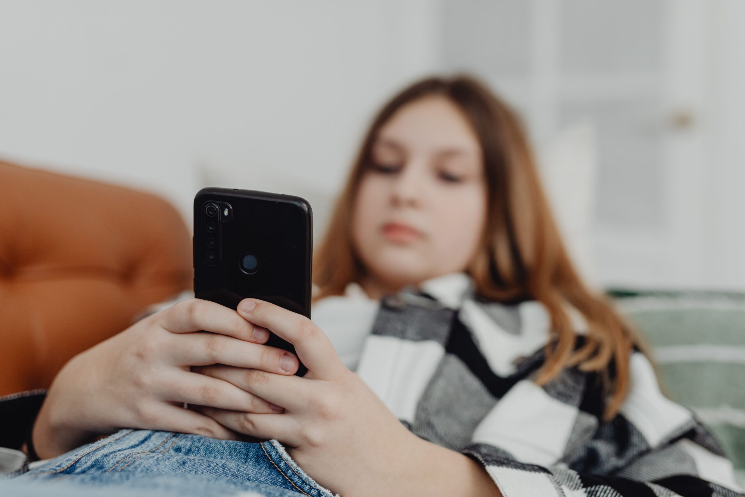 Woman checking phone while lying on couch.