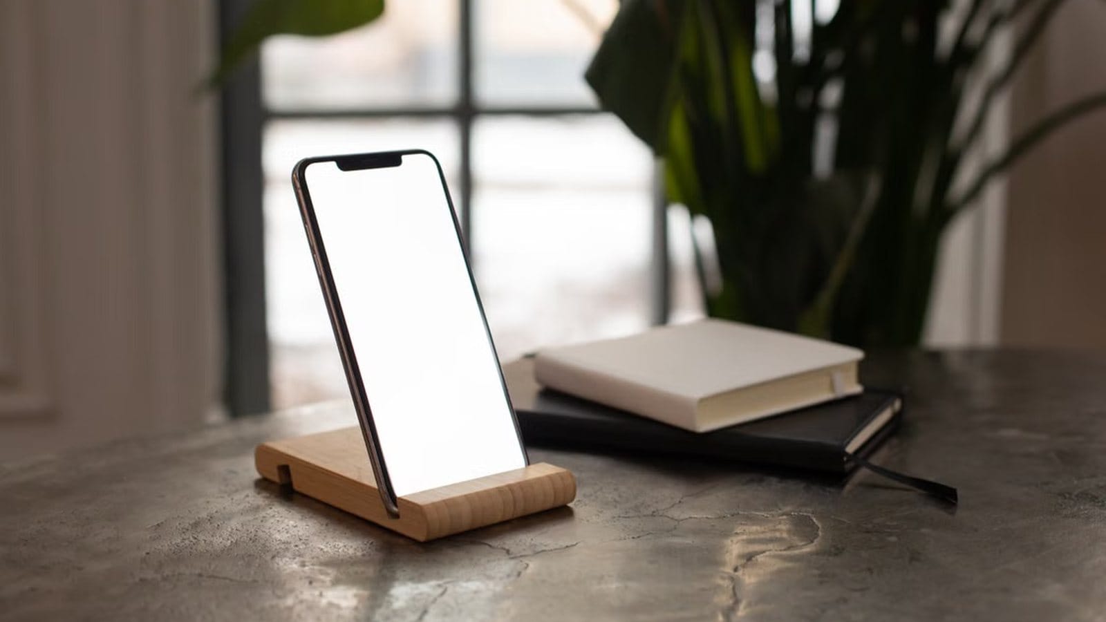 Smartphone on a stand beside notebooks in a quiet workspace